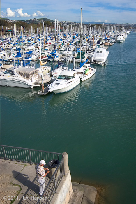 Fisherman on the pier with boats at anchor in the background