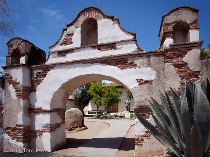 Entrance archway. The stucco has obviously been repaired, with the original brickwork showing through. In the background is a...